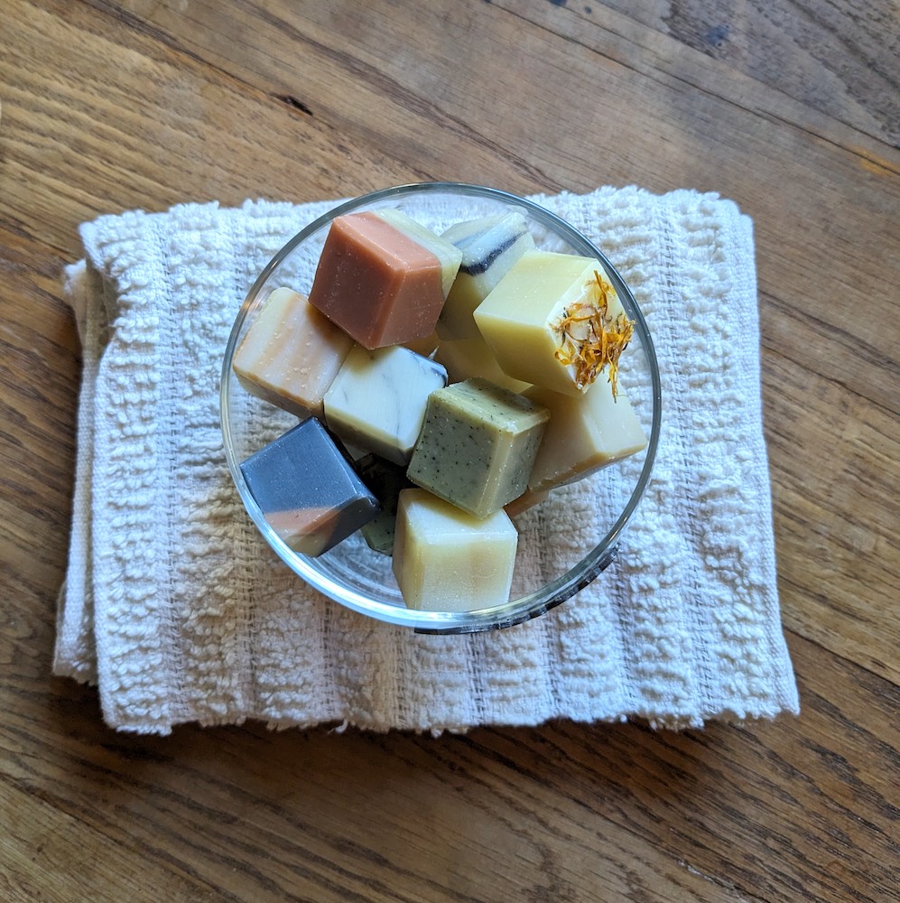 petits cubes de savons colorés disposés dans une coupelle en verre