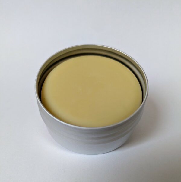 baume solide de couleur jaune clair dans sa boîte en aluminium ouverte