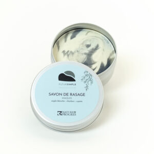 savon de rasage ouvert dans sa boîte aluminium, étiquette bleu ciel. le savon est marbré. photo sur fond blanc